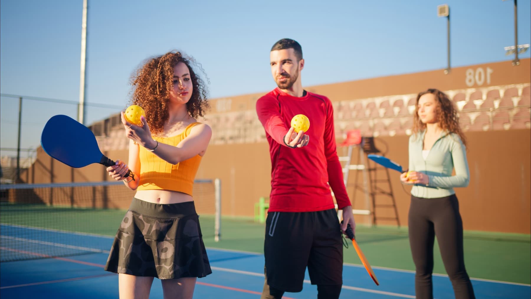 Friends sharing a laugh between points on a sunny pickleball court